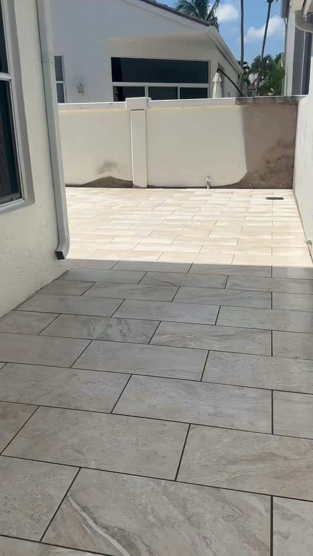 Newly tiled outdoor patio area with a clear sky and palm trees in the background.