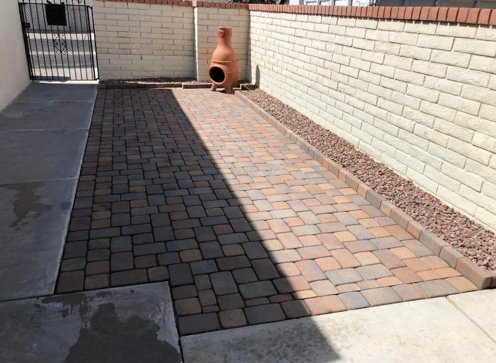 Paved outdoor area with stone pathway and clay decorative pot against a brick wall.