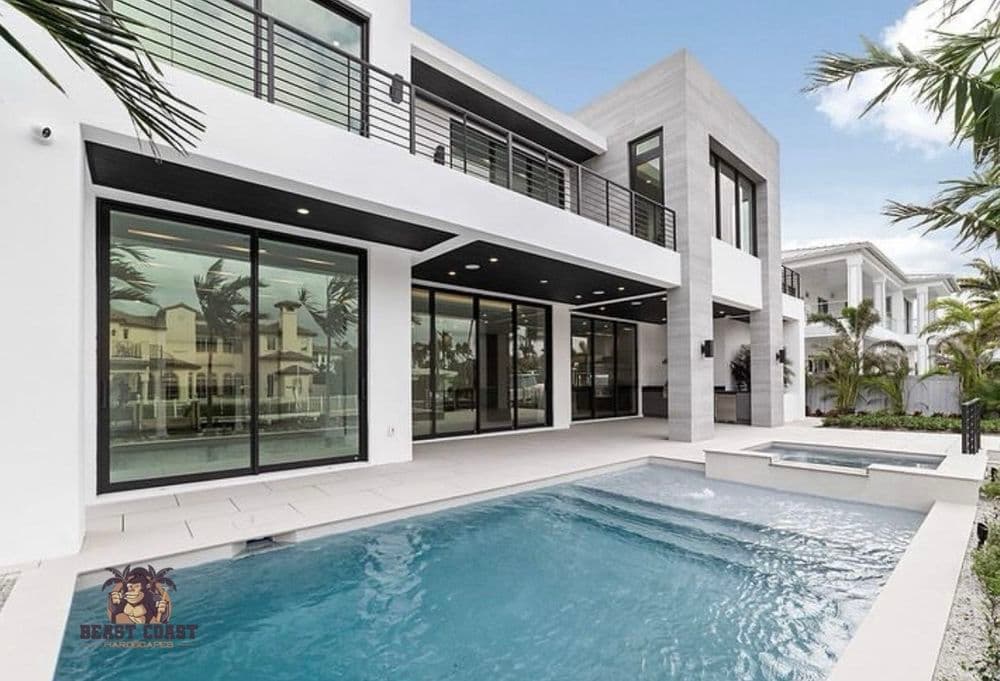 Modern luxury home exterior with pool and large glass windows in a tropical setting.