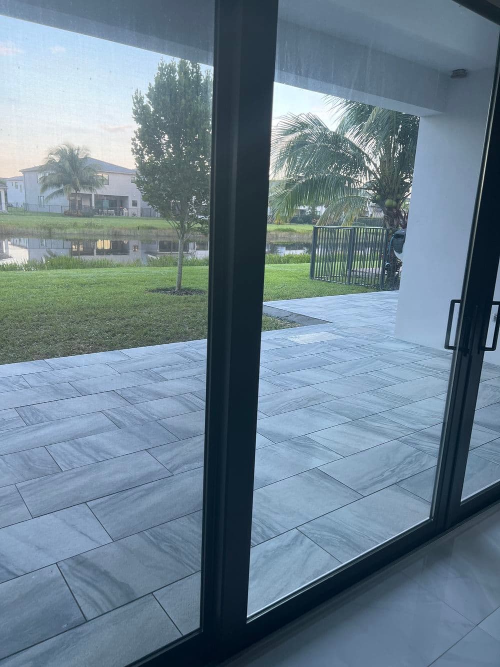 Modern patio view with marble tiles overlooking a serene waterway and lush landscaping.