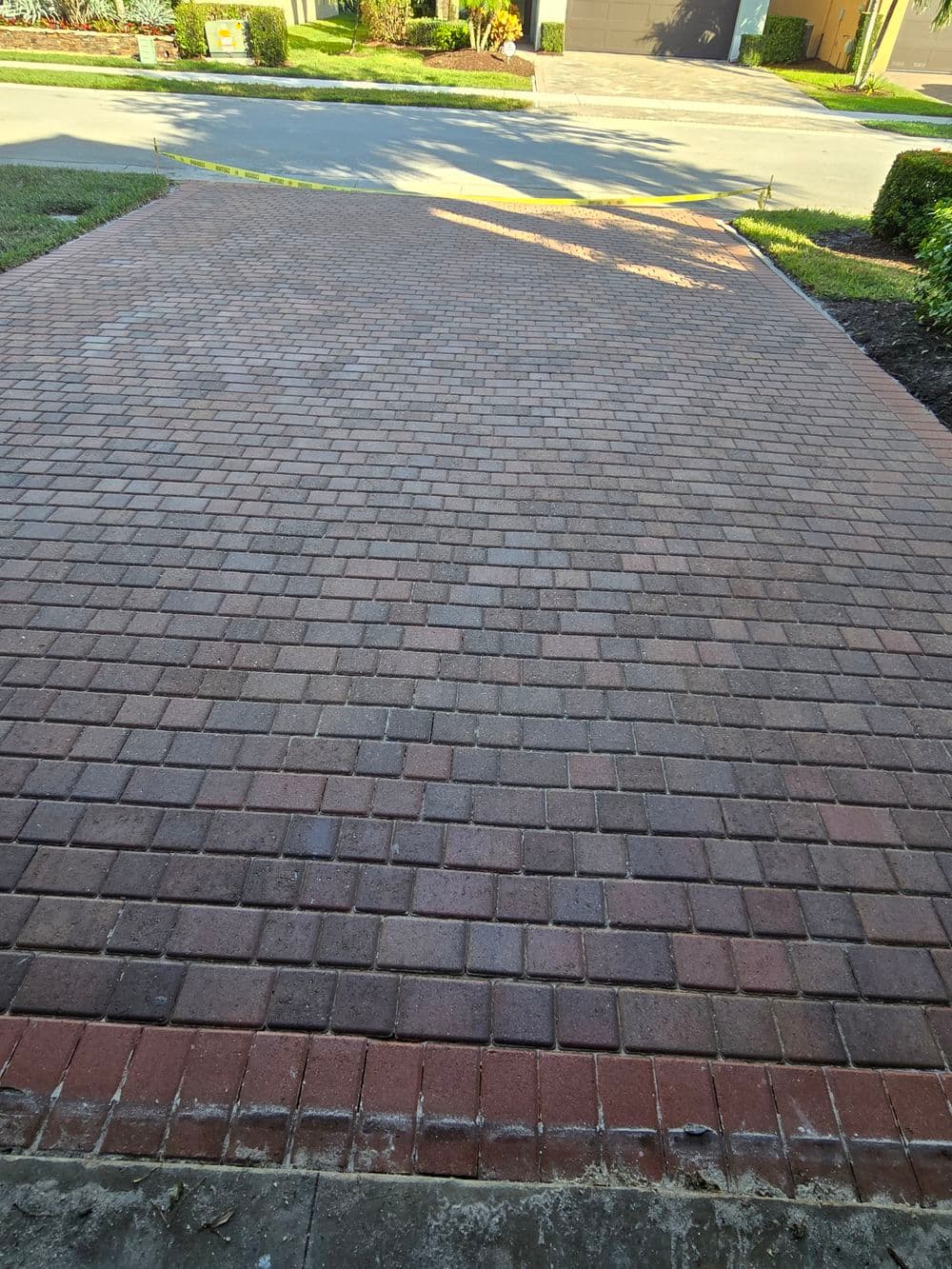 Paved driveway with interlocking bricks, featuring a mix of brown and red tones.