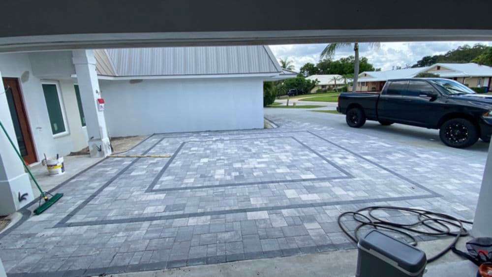 Newly paved driveway with decorative patterns and a black truck parked nearby.